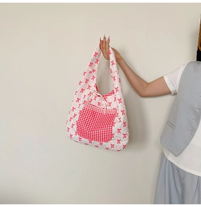 Detail of floral tote bag showing red bow patterns and a red checkered front pocket