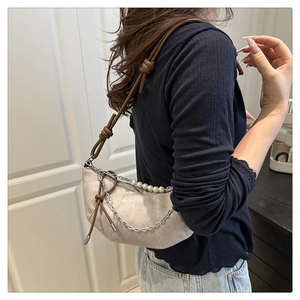 Dettaglio borsa a mezzaluna in camoscio beige con manico di perle e catena in metallo