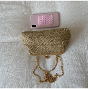 Macro shot of gold woven evening bag with dual ball clasp, ring handle and fine chain