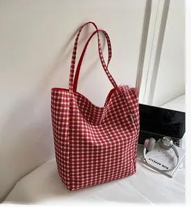Detail shot of a red gingham canvas tote bag with a spacious interior and woven label