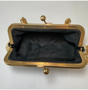 Macro shot of gold metal clasp and black lining of a woven party evening clutch bag