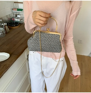 Detail of grey tweed shell-shaped bag with gold metal frame and ball clasp hardware