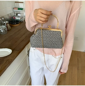 Macro detail of retro woven tweed texture and golden metal handle on women's chain handbag