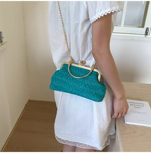Detail view of woven turquoise shell bag with gold metal frame and elegant chain strap