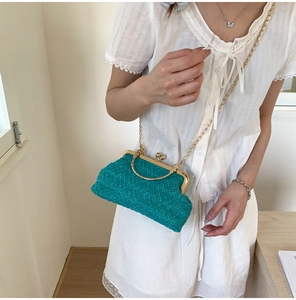 Detail of turquoise woven shell bag with gold round handle and metal clasp closure