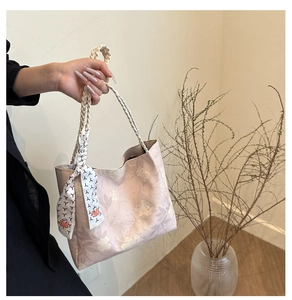 Gros plan détaillé d'un sac cabas fleuri rose avec poignées en corde et foulard en soie