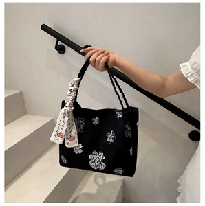 Détail du sac cabas en toile noire avec imprimé floral et poignée en corde tressée