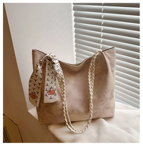 Détail du sac cabas fleuri rose avec anses tissées et élégant foulard en soie imprimé