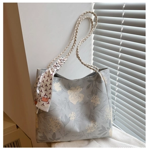 Détail du cabas floral avec poignées tressées et accessoire foulard en soie décoratif