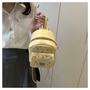 Vue détaillée d'un mini sac à dos jaune matelassé avec rivets et chaîne argentée