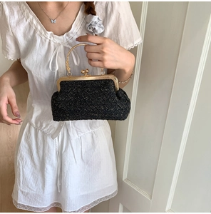 Detail of black tweed evening clutch bag with gold round handle and ball clasp closure