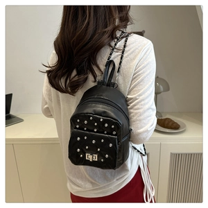 Détail du sac à dos matelassé noir avec clous argentés et bandoulière chaîne sur un mannequin