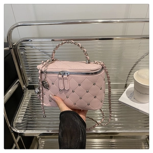 Détail du vanity bag rose matelassé avec rivets argentés et breloque rose élégante