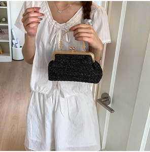 Detail of vintage evening clutch with shimmering black woven fabric and gold metal handle