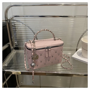 Détail du sac vanité rose matelassé avec clous argentés et poignée élégante en chaîne