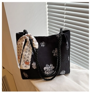 Détail du cabas noir en toile à fleurs avec un foulard blanc élégant sur la poignée