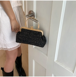 Detail of black woven tweed evening bag with vintage gold handle and metallic closure