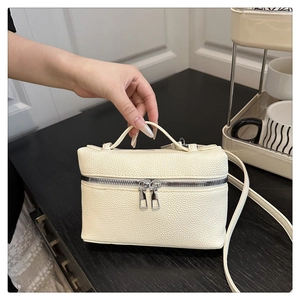 Detail of creamy white mini trunk bag showing pebbled leather texture and silver hardware