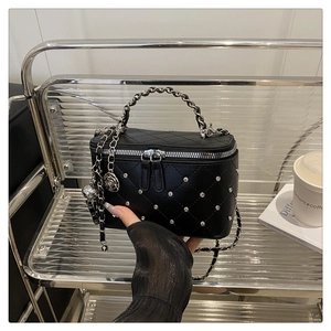 Détail du sac boîte en cuir matelassé noir avec clous argentés et poignée chaîne