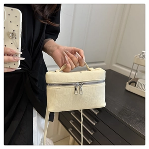 Detail of cream white pebbled leather bag with top handle and metallic zipper