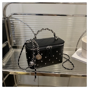 Détail du sac vanité noir matelassé avec strass argentés et pendentif camélia