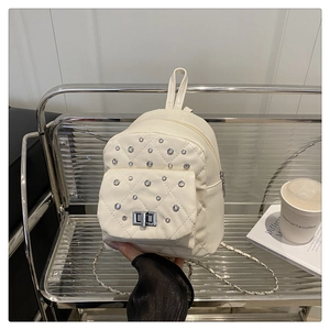 Détail du mini sac à dos blanc matelassé avec strass argentés et bandoulière chaîne