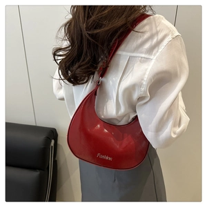 Détail d'un sac hobo en cuir verni rouge porté par un mannequin pour un look moderne chic