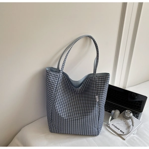 Detailed view of blue plaid canvas tote bag with fashion label and side pocket detail