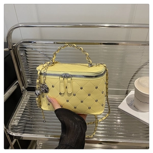 Détail du sac en cuir matelassé jaune avec rivets argentés et pendentif rose noire