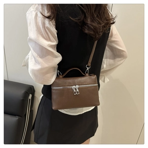 Detail of brown litchi pattern leather crossbody bag with dual silver zippers