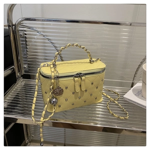 Gros plan sur le sac matelassé jaune avec clous métalliques et pendentif rose argenté