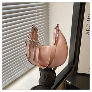 Close-up of pink crescent underarm bag featuring a metallic bow and Fashion print