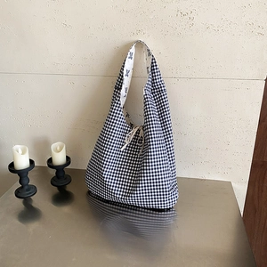Black and white gingham tote bag with drawstring closure on a metallic tabletop