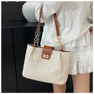 Détail d'un sac en paille tissé beige avec des lanières en cuir et un fermoir doré