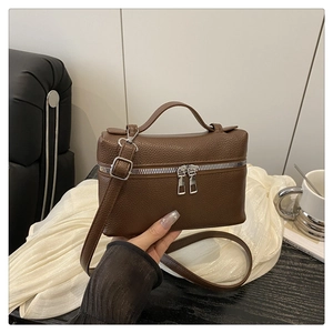 Detail of brown litchi pattern leather bag with silver double zippers and top handle