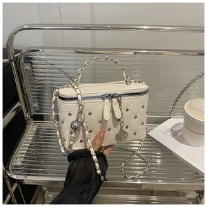 Détail d'une petite trousse matelassée blanche avec garniture argentée et charme rose