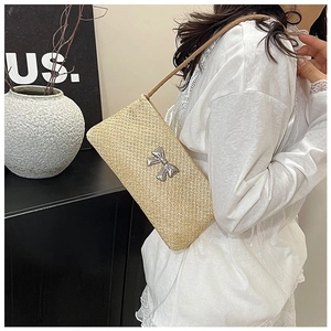 Close-up of minimalist straw shoulder bag featuring a silver bow metal buckle detail