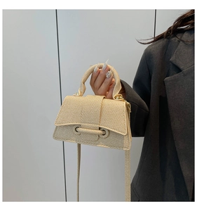 Detail shot of the hand-woven straw trapezoid handbag texture and round handle design