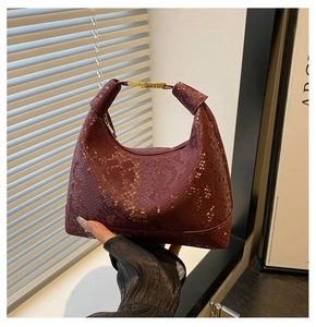 Détail du sac à main bordeaux texture serpent avec fermoir doré et marquage de marque