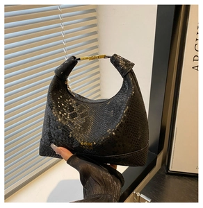 Gros plan du sac hobo noir avec texture serpent et poignée en métal doré chic