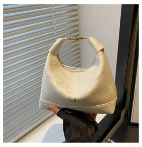 Gros plan sur la texture serpent blanc avec logo doré et détails métalliques du sac