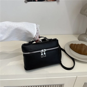 Elegant black lychee textured leather crossbody bag with silver zipper in lifestyle setting