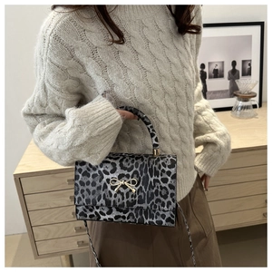Detailed view of leopard print shoulder bag with gold bow clasp and matching strap