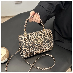 Detail of leopard print handbag featuring a gold bow metal clasp and textured strap