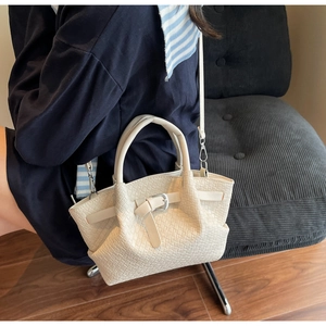 Détail du sac cabas en cuir tressé crème avec boucle sur un fauteuil en velours