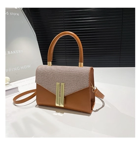 Detail of trendy crossbody bag showing textured tweed flap and gold metal buckle lock