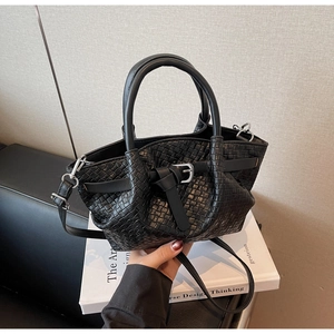 Détail du sac seau tressé noir montrant la texture et la boucle en métal argenté
