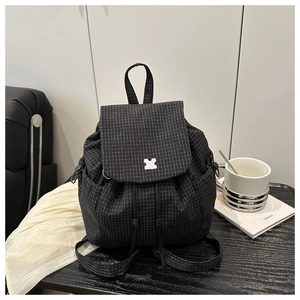 Detail of drawstring closing and metal buckle on black checkered fashion backpack