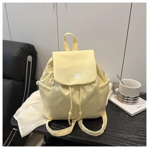 Macro shot of light yellow nylon backpack showing drawstring closure and ribbon detail