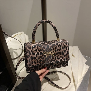 Leopard print crossbody bag with golden bow detail and structured top handle